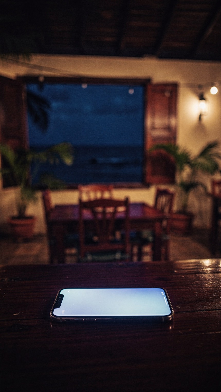 Une salle de restaurant fermée la nuit ; sur une table, un téléphone allumé.